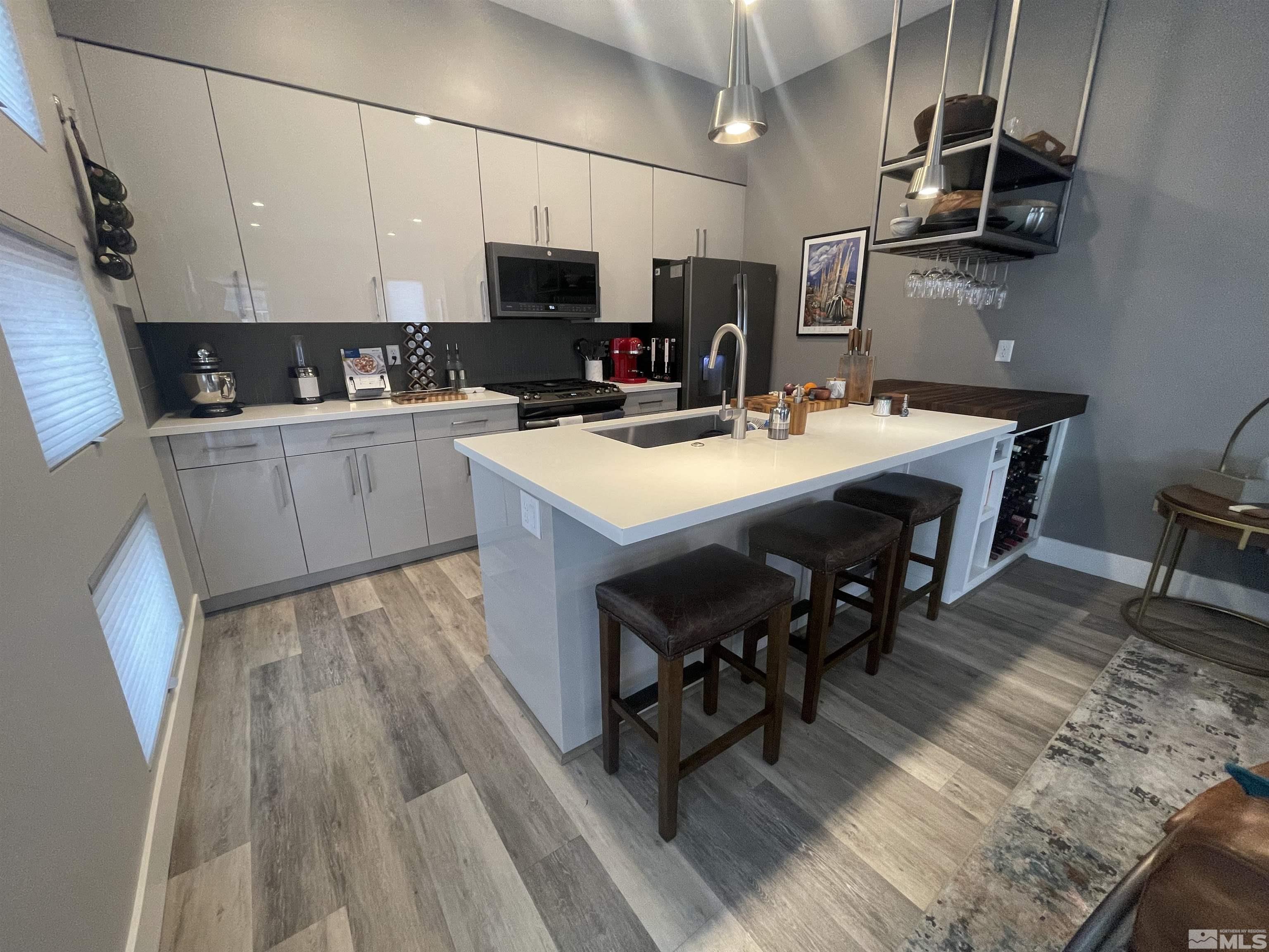 123 Martin Street Reno, NV 89509 - Photo 9 of 31 a kitchen with stainless steel appliances a stove a sink dishwasher a microwave oven with a dining table and chairs with wooden floor