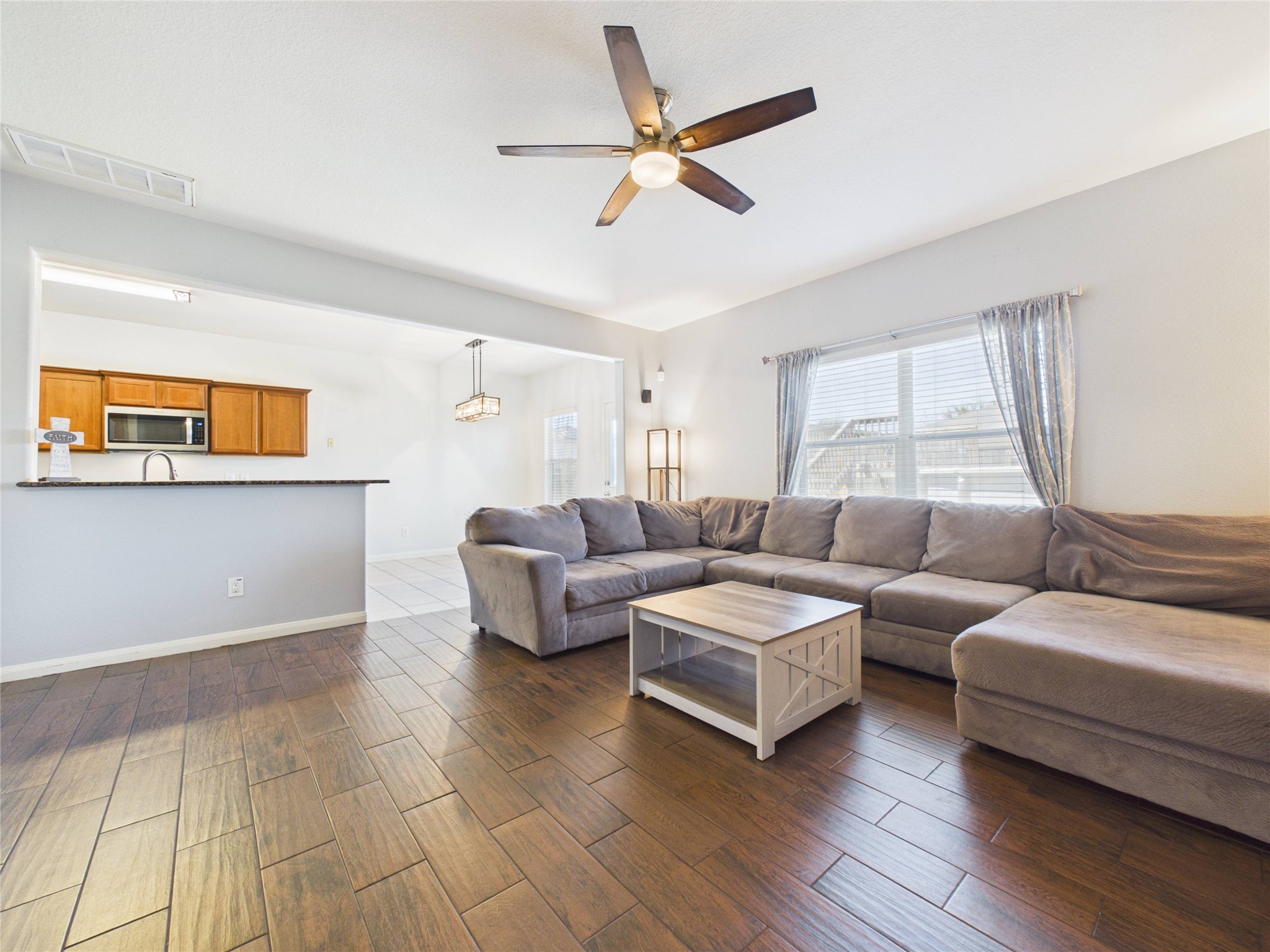 911 Marigold Road Baytown, TX 77521 - Photo 12 of 32 The spacious living area with tile floors flows seamlessly into a well-appointed kitchen featuring wooden cabinets and a breakfast bar, creating an open layout ideal for both everyday living and entertaining.