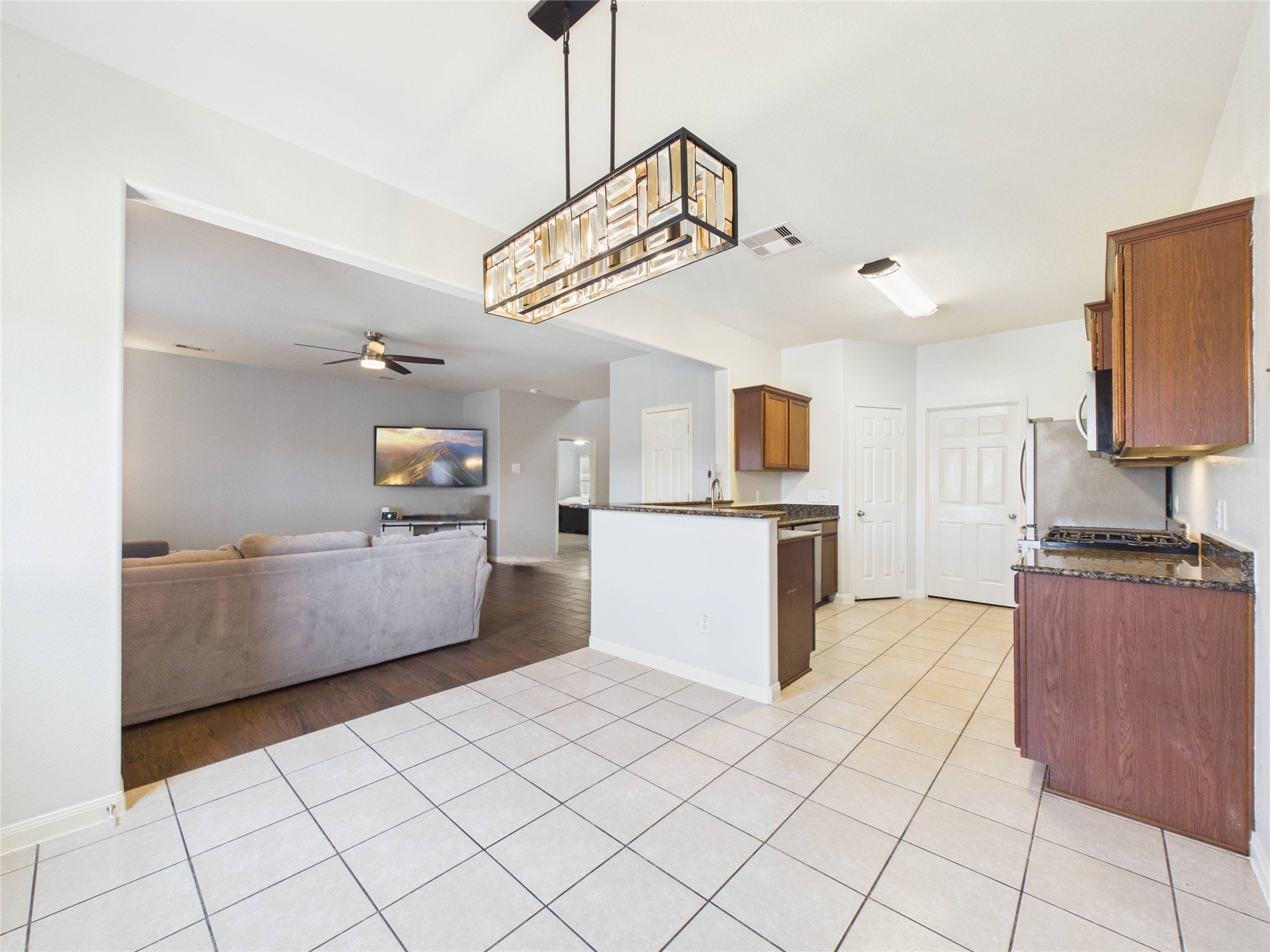 911 Marigold Road Baytown, TX 77521 - Photo 13 of 32 The open-concept living space featuring a tiled dining area, a modern kitchen with granite countertops and stainless steel appliances, functional layout ideal for both everyday living and entertaining.