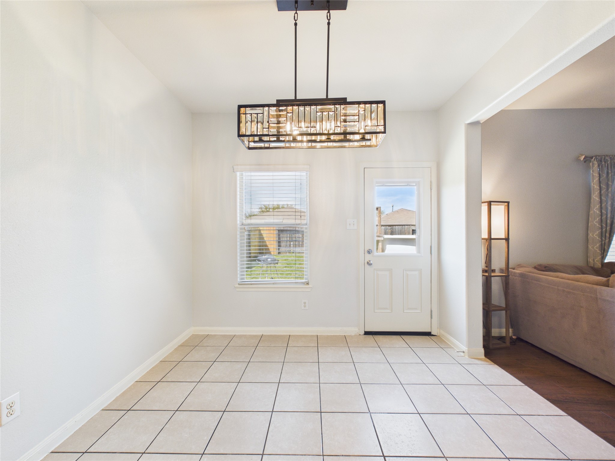911 Marigold Road Baytown, TX 77521 - Photo 14 of 32 A bright dining/eat in kitchen area with tiled flooring, a modern rectangular chandelier.