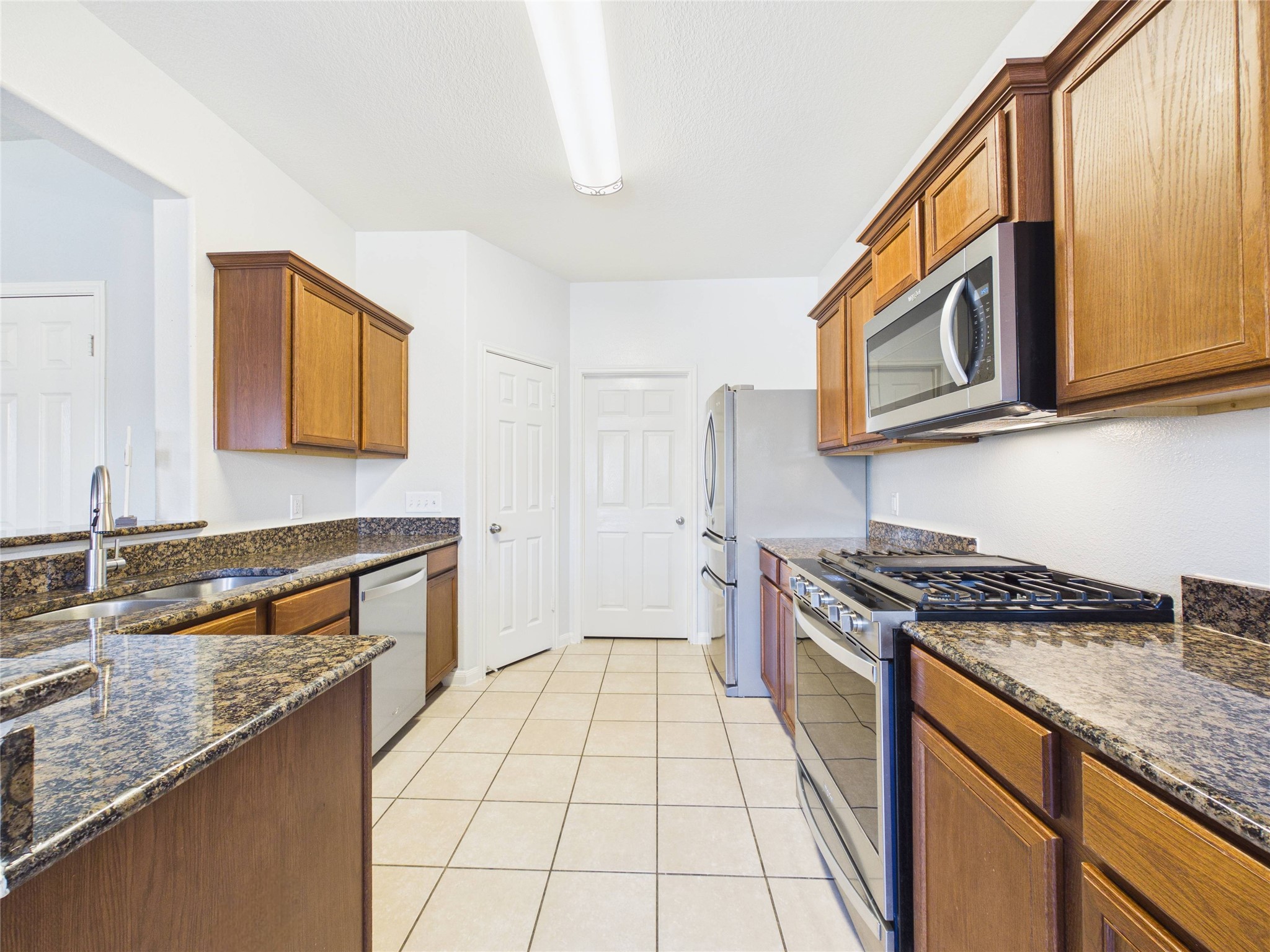 911 Marigold Road Baytown, TX 77521 - Photo 18 of 32 The kitchen opens to a walk-in pantry and laundry room, providing convenient access to storage and utility spaces.