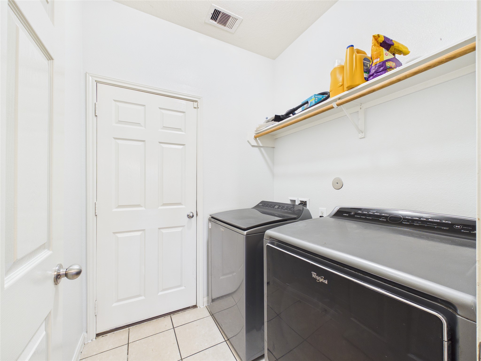 911 Marigold Road Baytown, TX 77521 - Photo 20 of 32 The laundry room with tile flooring, shelving for storage, and clean white walls provides a bright, functional space for laundry and household maintenance.