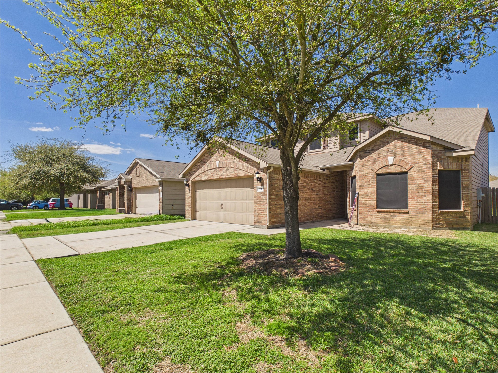911 Marigold Road Baytown, TX 77521 - Photo 2 of 32 This welcoming home features a brick exterior with a two-car garage, set on a well-maintained lawn with mature trees.