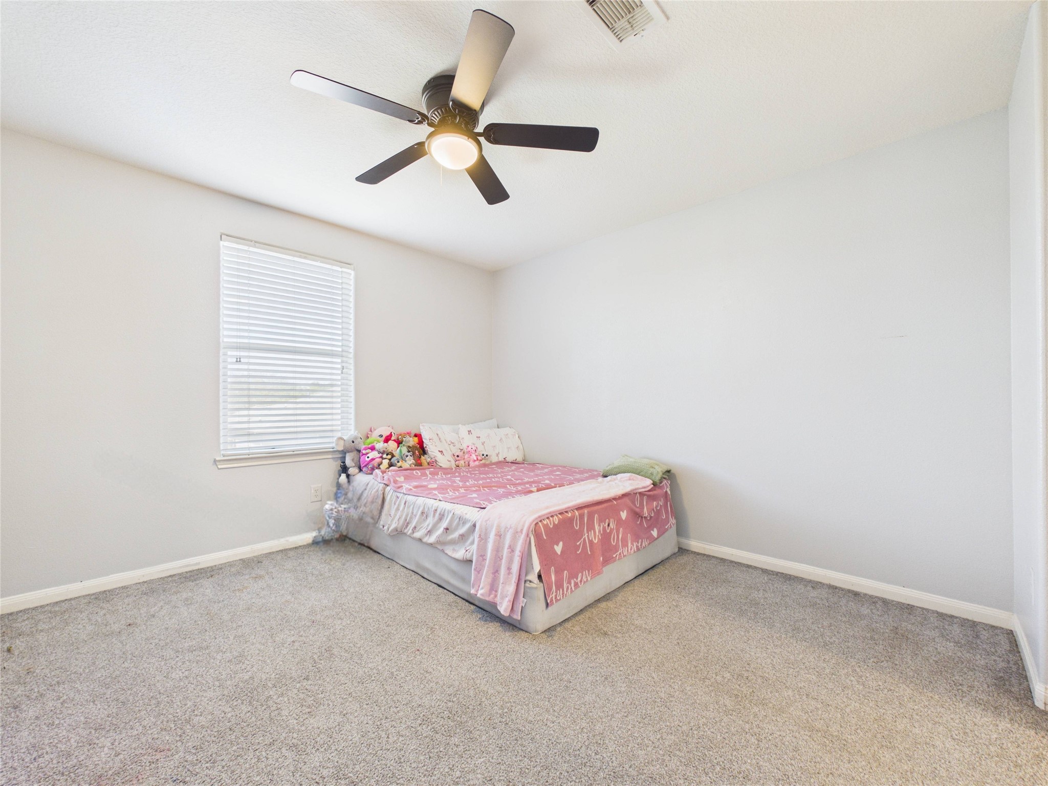 911 Marigold Road Baytown, TX 77521 - Photo 24 of 32 This bedroom features a neutral color palette with carpeted flooring, a ceiling fan, and ample natural light from a window.