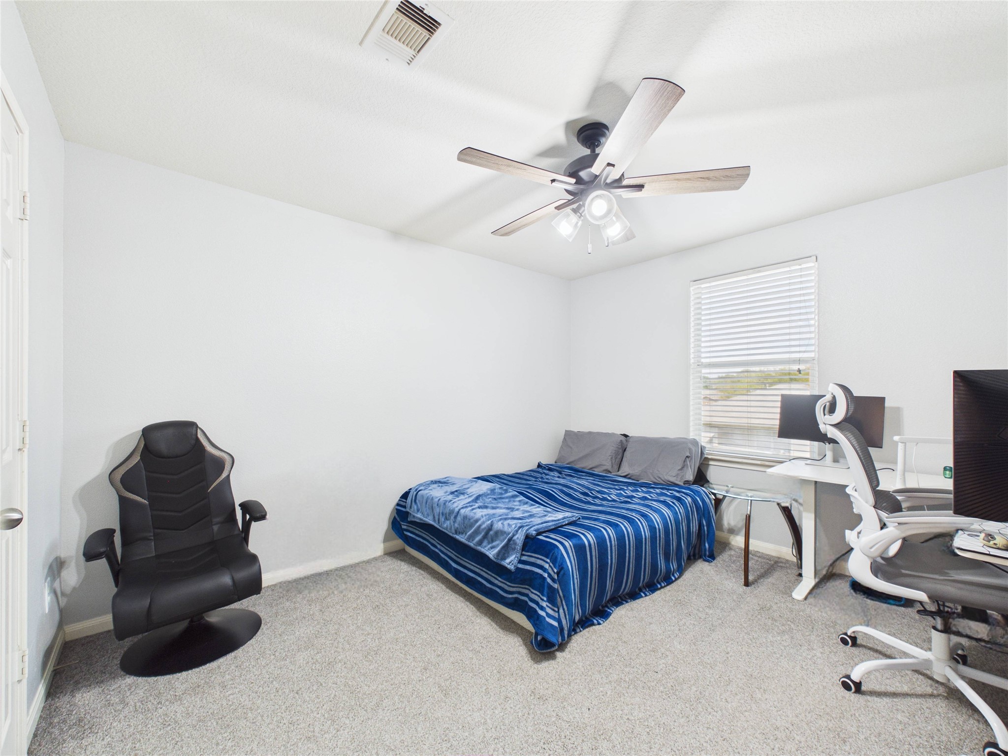 911 Marigold Road Baytown, TX 77521 - Photo 26 of 32 This bedroom features a cozy space with neutral walls and carpeted flooring, a ceiling fan, and natural light from a window.