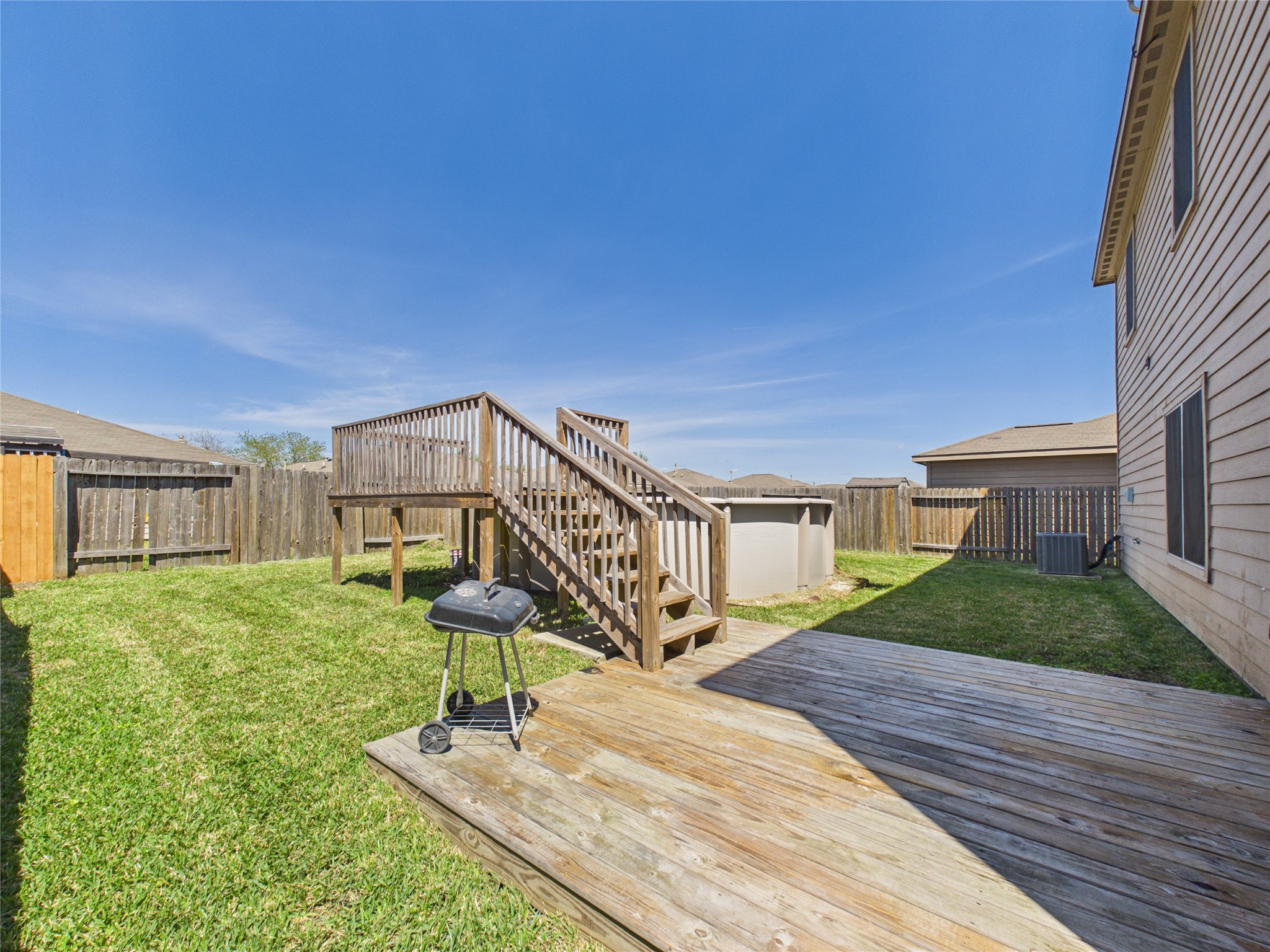 911 Marigold Road Baytown, TX 77521 - Photo 29 of 32 Spacious backyard featuring a wooden deck, grassy area, above-ground pool, and wooden fencing for privacy. Perfect for outdoor activities and relaxation.