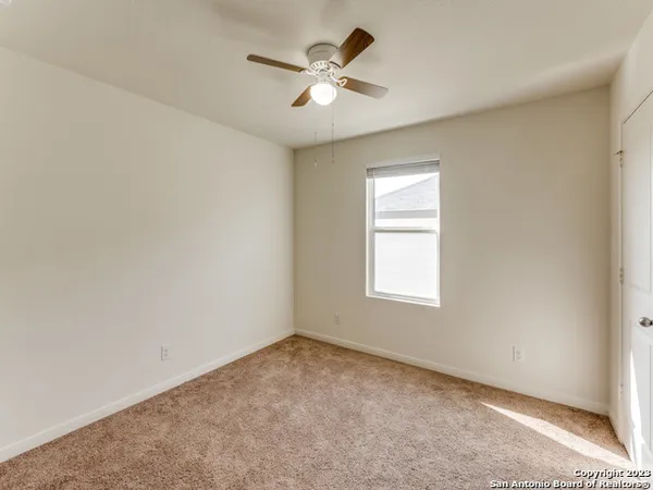 an empty room with a window and a ceiling fan
