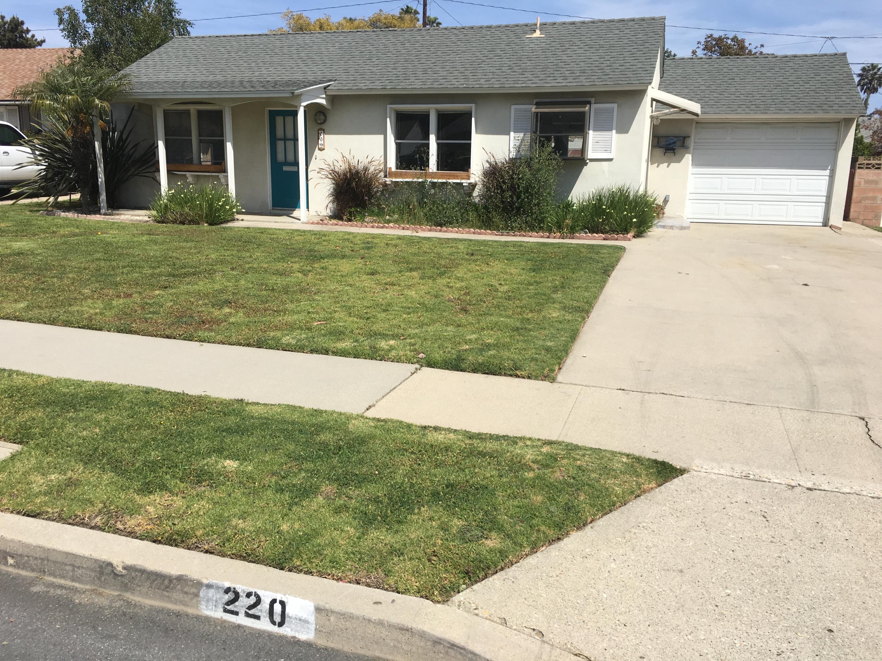 a view of a house with a yard and potted plants