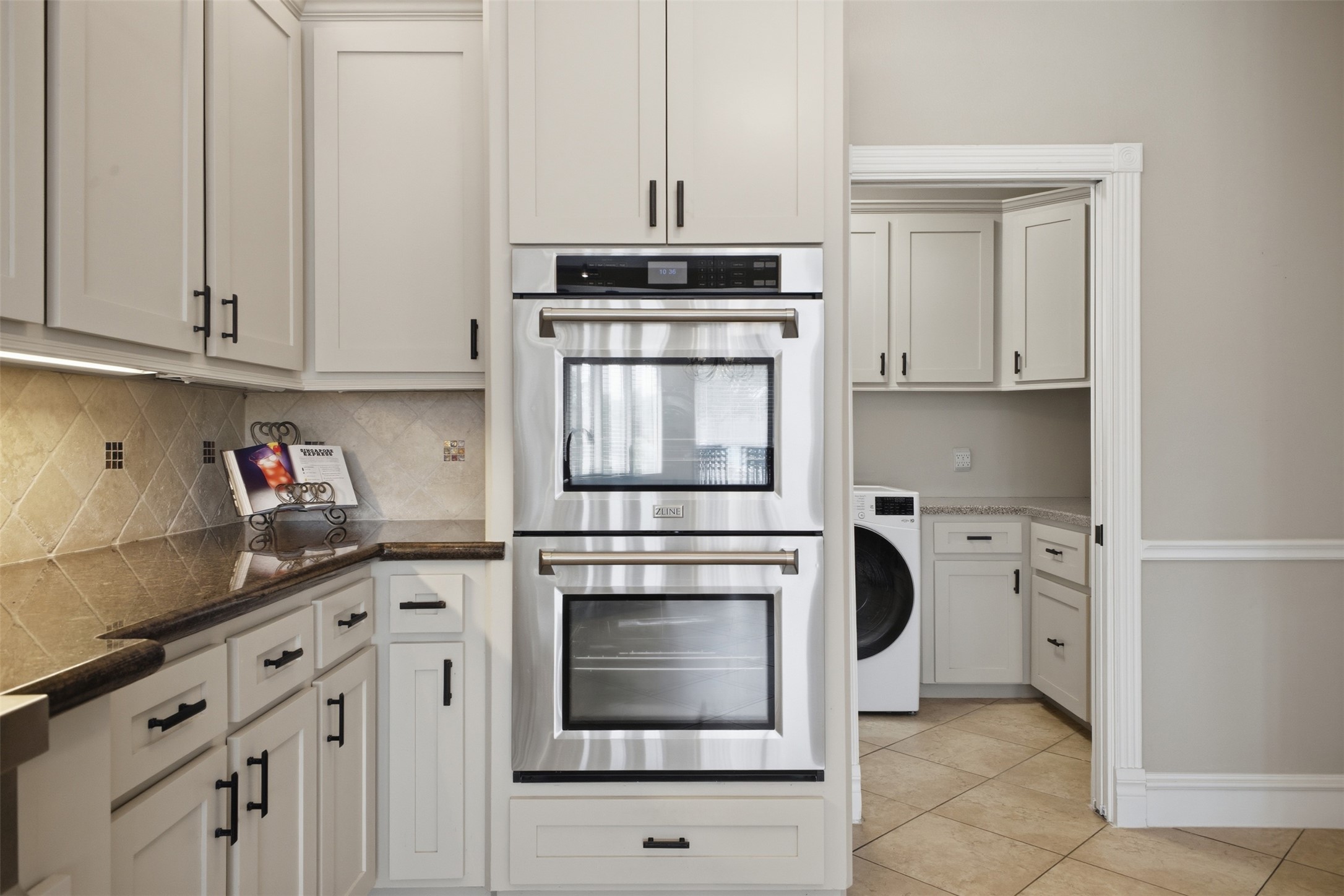 12710 Aries Loop Willis, TX 77318 - Photo 16 of 40 This kitchen features white cabinetry with dark hardware, a built-in double oven, and a tiled backsplash
