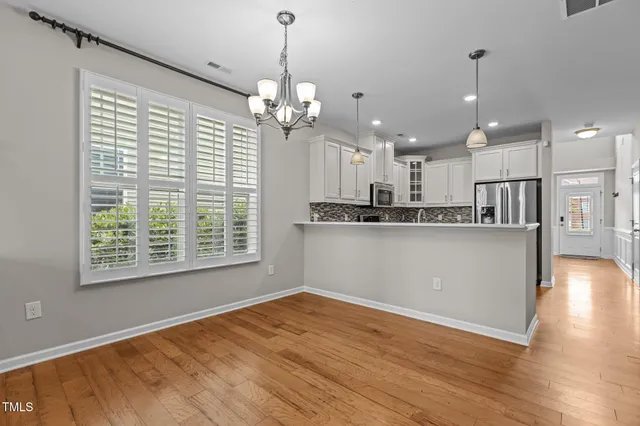 a view of a kitchen with stainless steel appliances granite countertop a refrigerator a oven a stove and a wooden floors