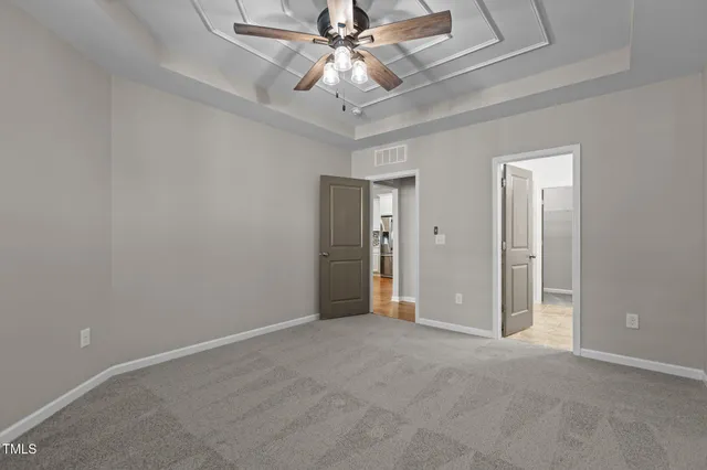 a view of an empty room and chandelier fan