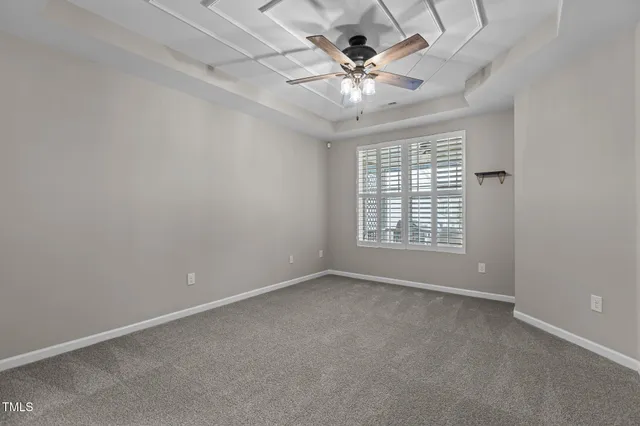 an empty room with a chandelier fan and windows