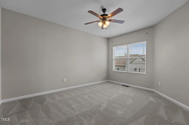 an empty room with a chandelier fan and windows
