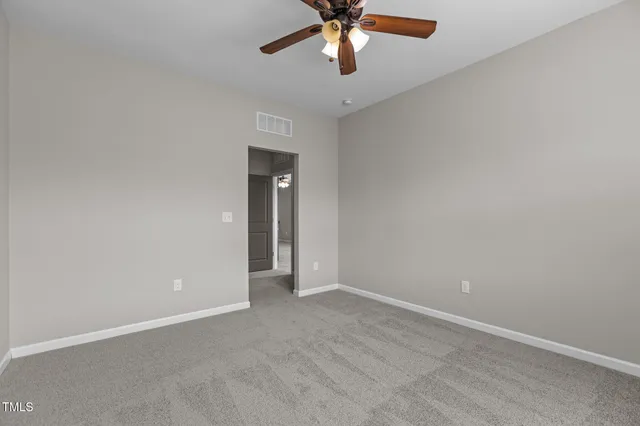 a view of an empty room and chandelier fan
