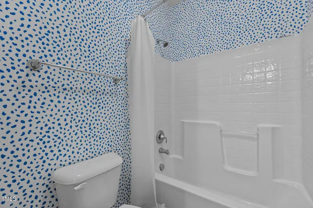 a white toilet sitting next to a shower