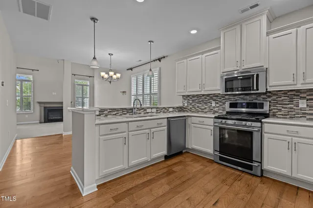 a kitchen with stainless steel appliances granite countertop a stove a sink and white cabinets