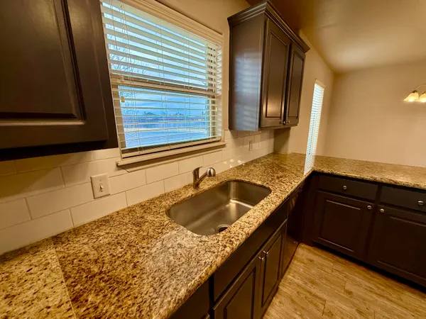 a kitchen with granite countertop sink and cabinets