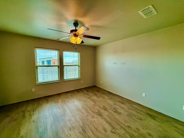 a view of an empty room with window and wooden floor