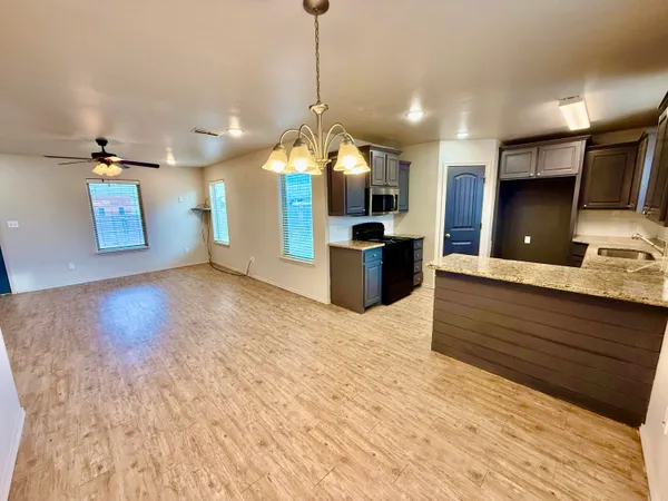 a kitchen with stainless steel appliances kitchen island granite countertop a sink dishwasher a refrigerator and a wooden floor
