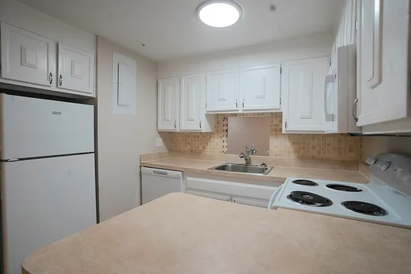 a kitchen with a sink a refrigerator and cabinets