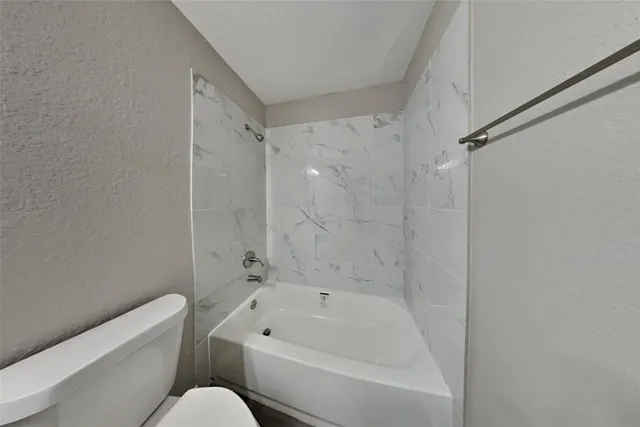 a bathroom with a bathtub shower sink vanity and toilet