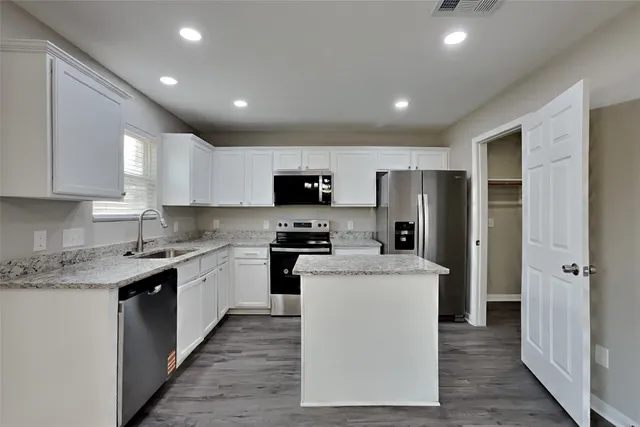 a kitchen with a sink a refrigerator and cabinets