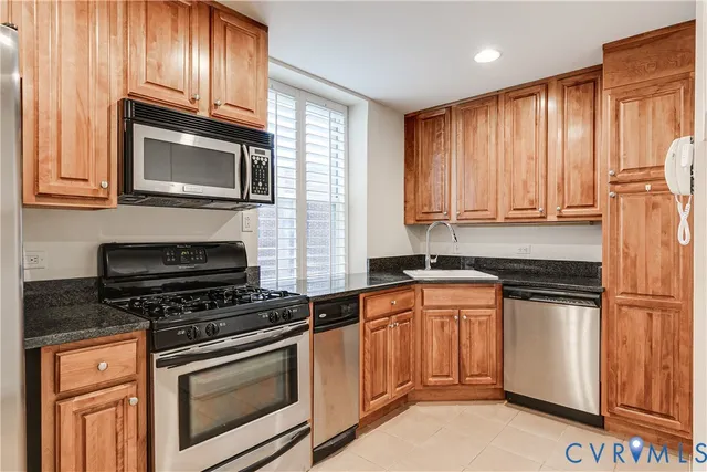 a kitchen with granite countertop a refrigerator and a stove top oven