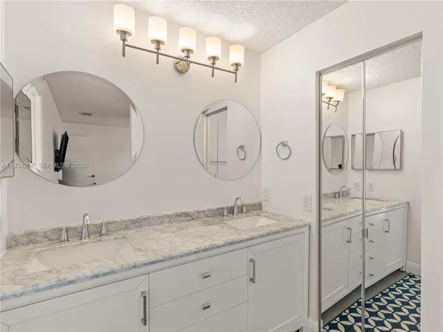 a bathroom with a granite countertop double vanity sink and mirror
