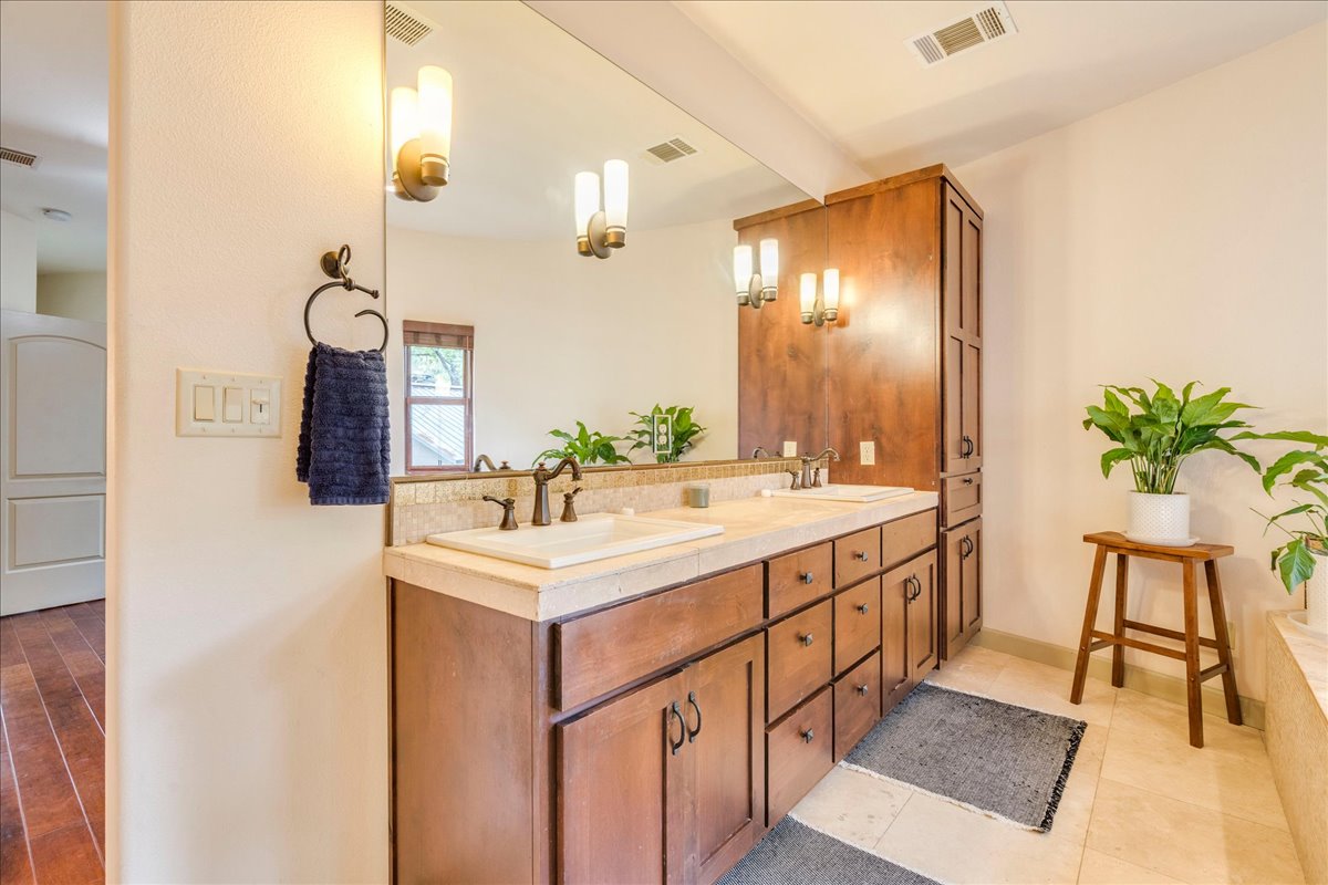 3012 South 4th Street, Unit B Austin, TX 78704 - Photo 17 of 40 Dual vanity with integrated sinks, oil-rubbed bronze fixtures, a full-width wall mirror, wood-finish cabinetry, and a tall built-in storage cabinet