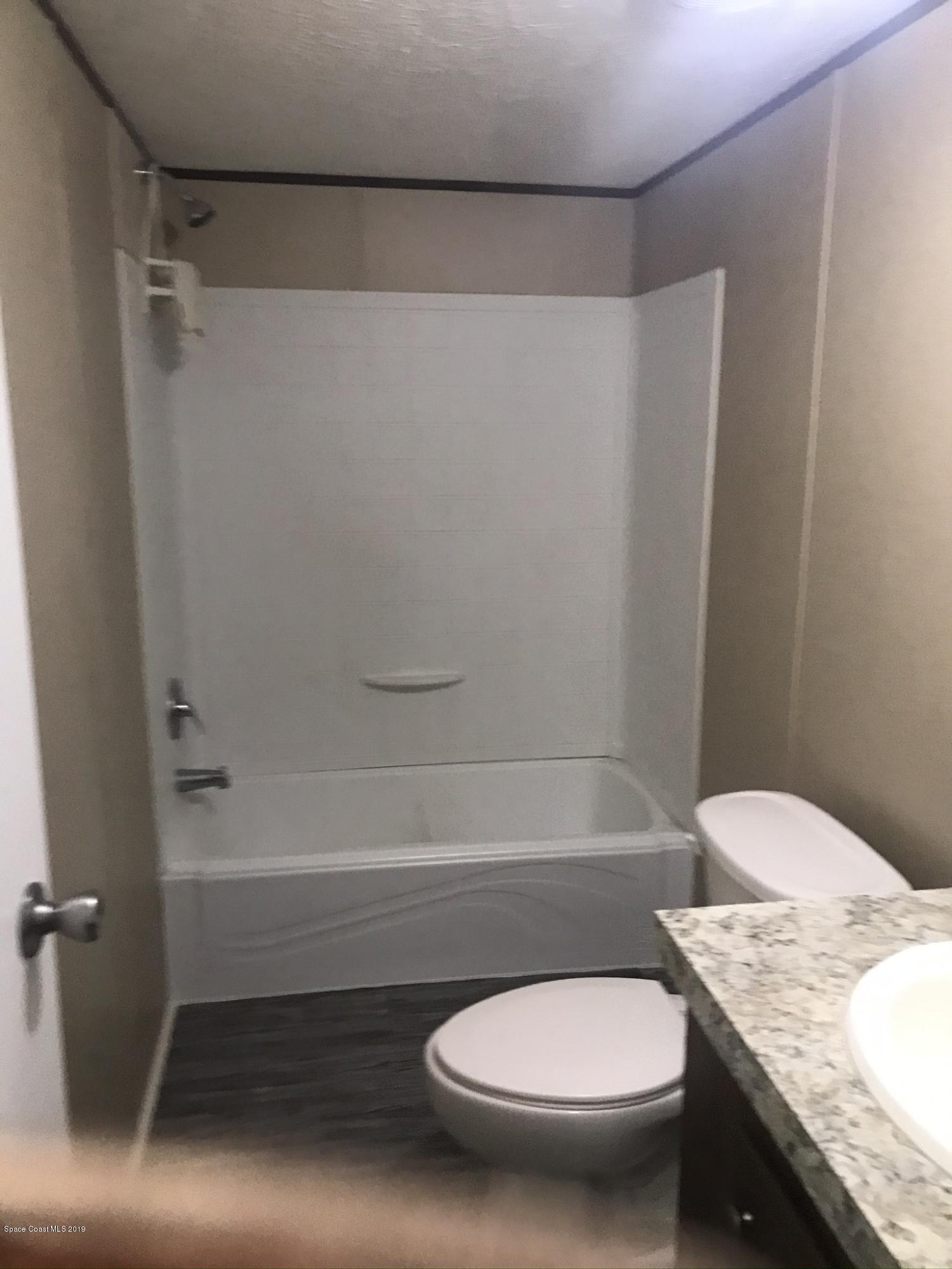 535 Baker Road Merritt Island, FL 32953 - Photo 17 of 34 a bathroom with a granite countertop toilet and a tub