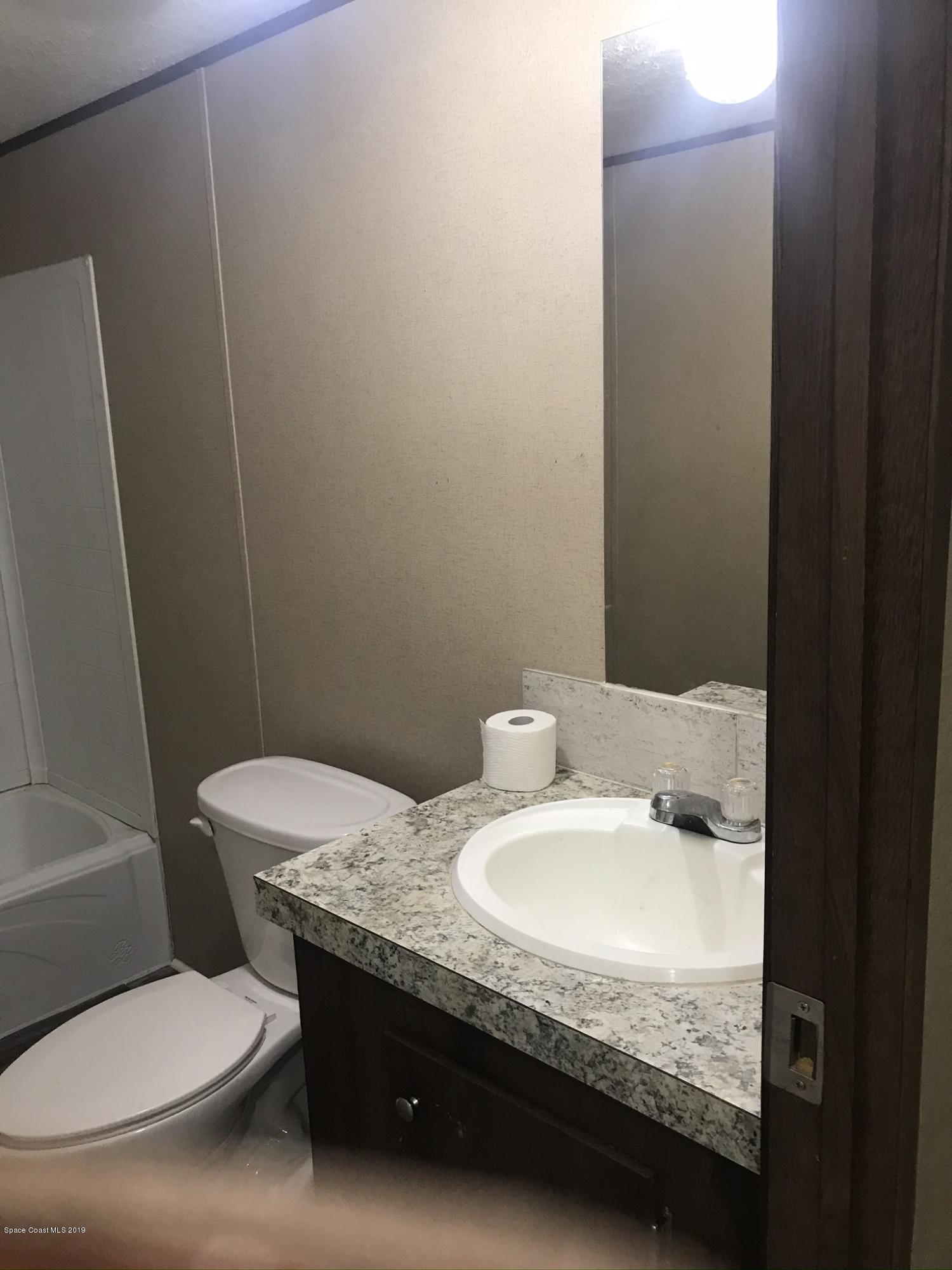 535 Baker Road Merritt Island, FL 32953 - Photo 18 of 34 a bathroom with a granite countertop toilet and a sink