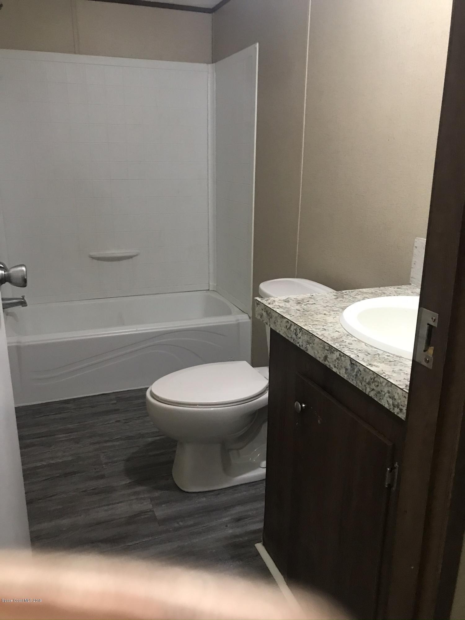 535 Baker Road Merritt Island, FL 32953 - Photo 19 of 34 a bathroom with a granite countertop toilet and a bathtub