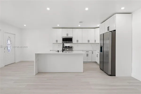 a kitchen with white cabinets and stainless steel appliances