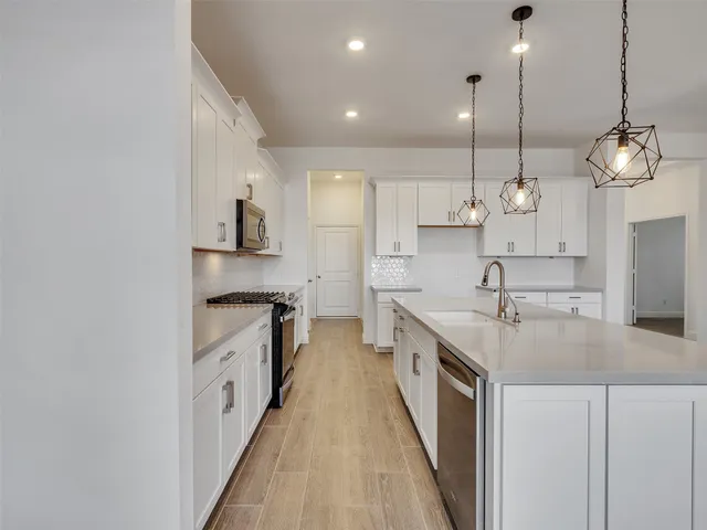 a large kitchen with kitchen island a stove a sink a center island and wooden floor