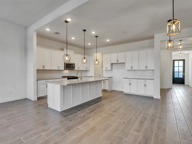 a large kitchen with cabinets wooden floor and stainless steel appliances
