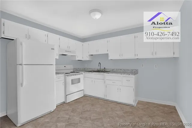 a kitchen with granite countertop white cabinets and white appliances