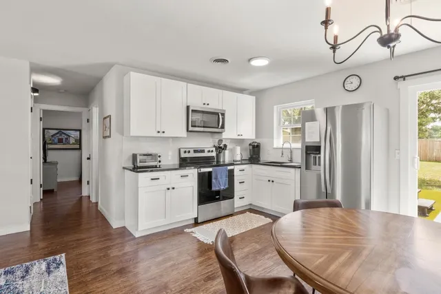 a kitchen with stainless steel appliances granite countertop a refrigerator a stove top oven a sink dishwasher and a refrigerator with wooden floor