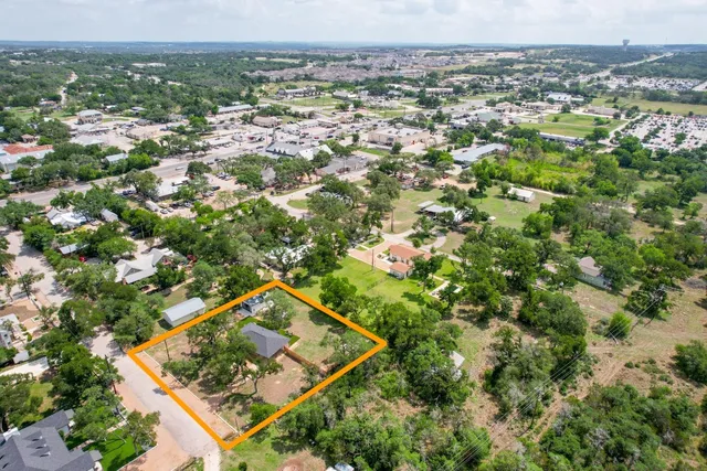 an aerial view of residential houses with outdoor space and trees