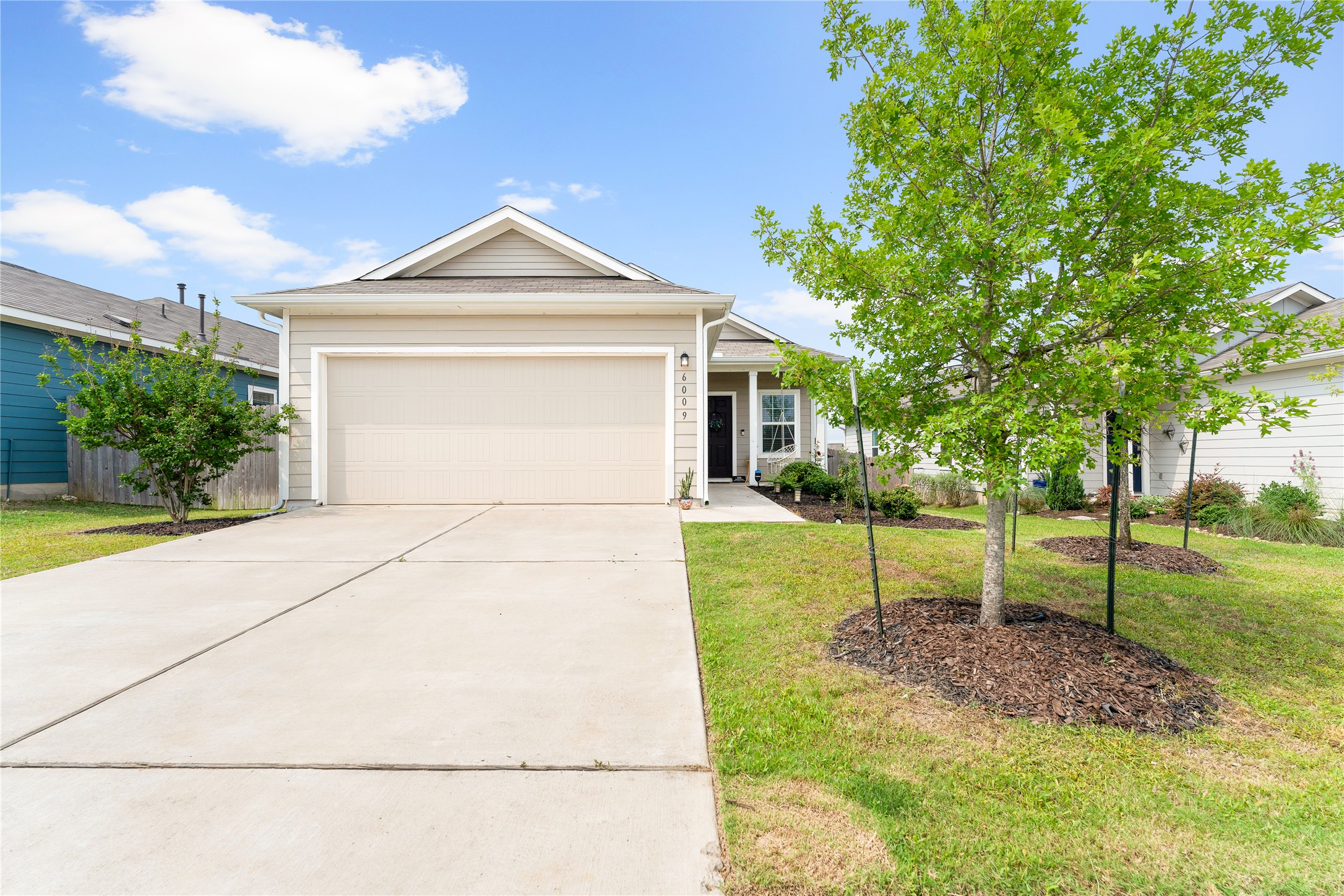 a view of a house with a yard and large tree