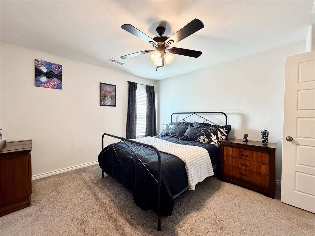 5664 Shore Point Trail Fort Worth, TX 76119 - Photo 14 of 29 a bedroom with bed and a chandelier