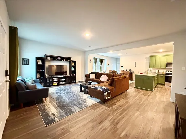 a living room with furniture flat screen tv and kitchen view