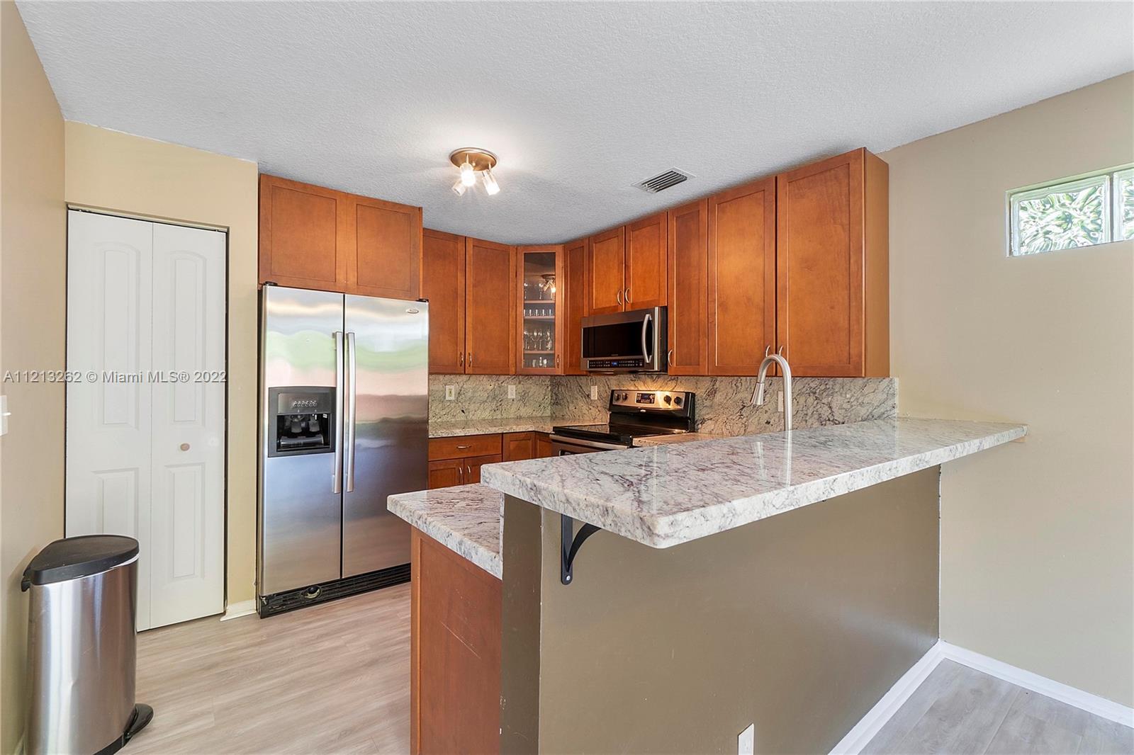 3123 Sunset Circle Margate, FL 33063 - Photo 13 of 58 a kitchen with stainless steel appliances granite countertop a refrigerator a stove and a sink with wooden floor