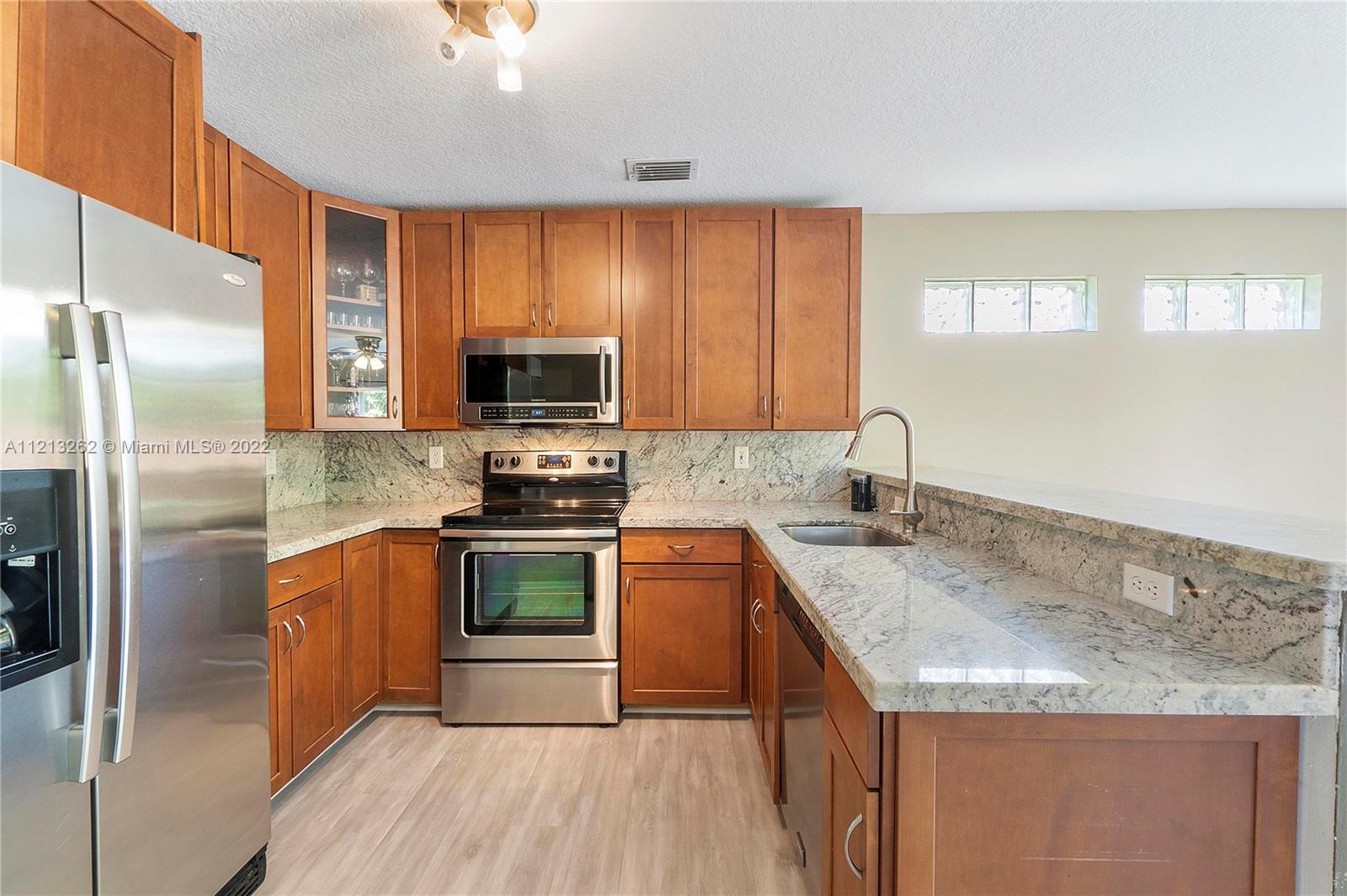 3123 Sunset Circle Margate, FL 33063 - Photo 14 of 58 a kitchen with stainless steel appliances granite countertop a sink stove and refrigerator