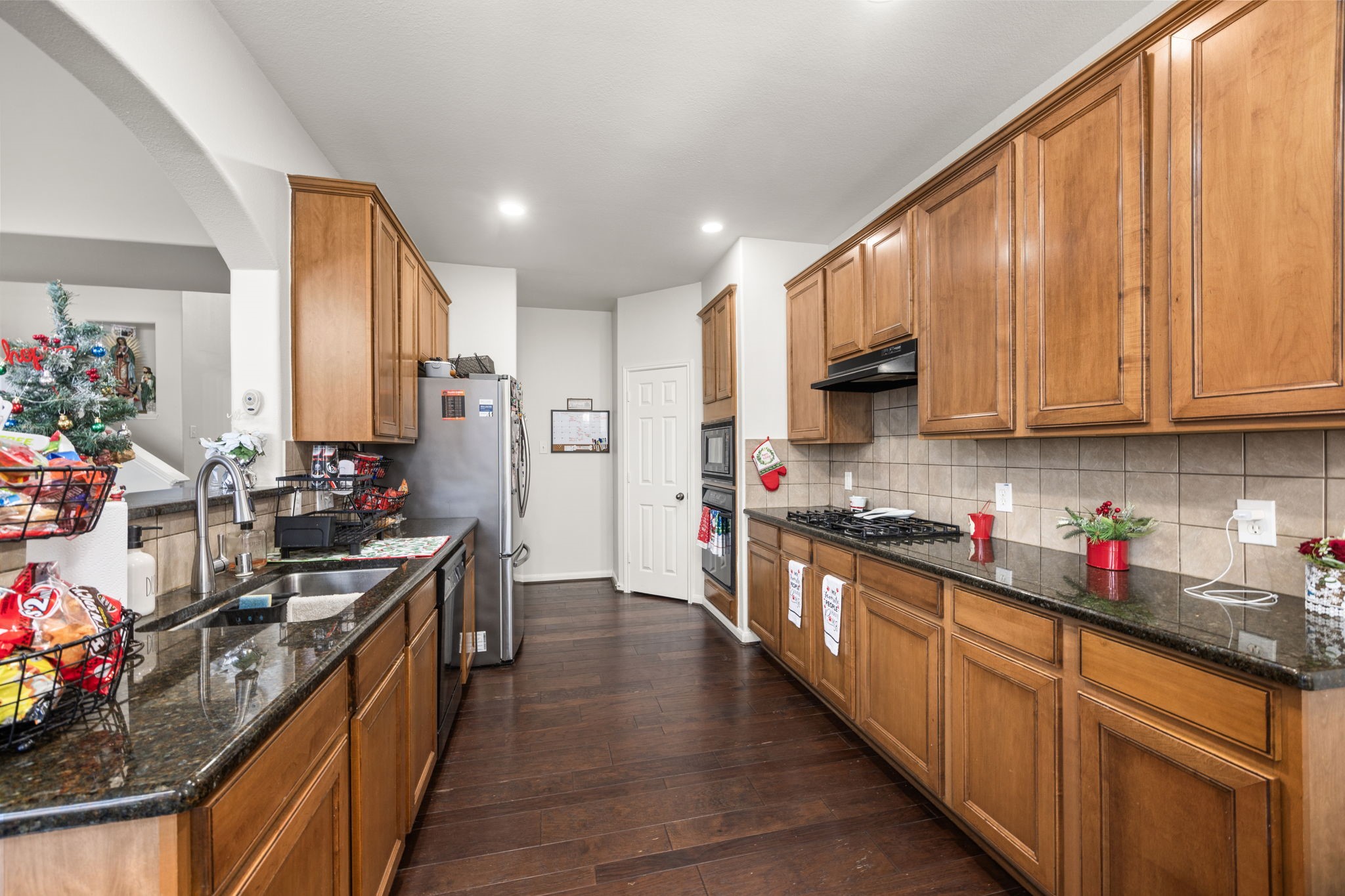 927 Spring Source Place Spring, TX 77373 - Photo 14 of 37 a kitchen with stainless steel appliances a sink dishwasher stove top oven refrigerator and cabinets with wooden floor
