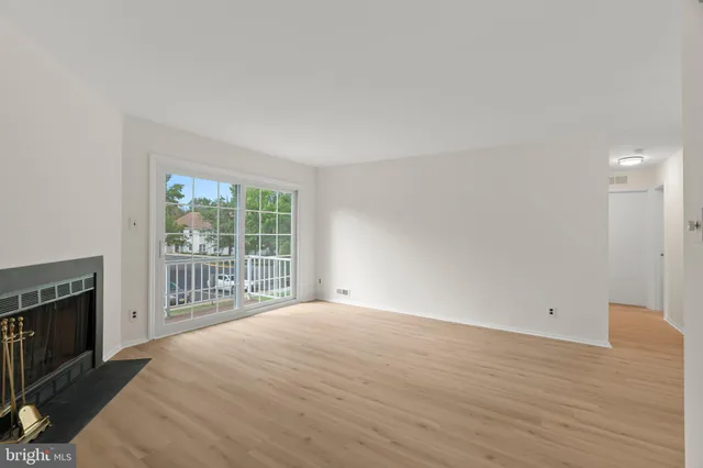 a view of empty room with wooden floor and fireplace