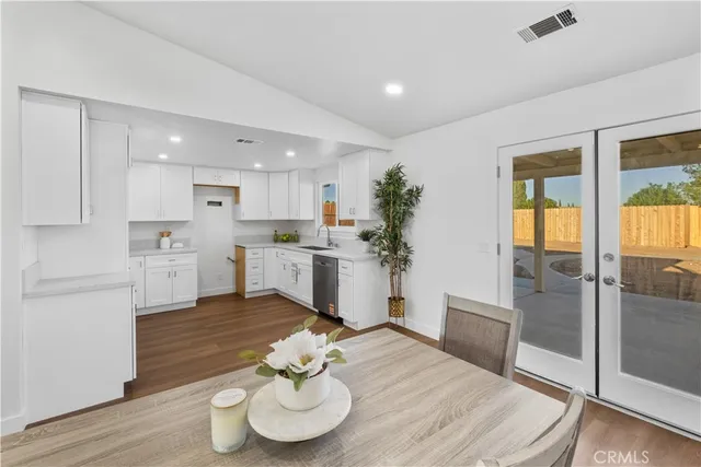 a kitchen with stainless steel appliances kitchen island granite countertop a table chairs and a refrigerator