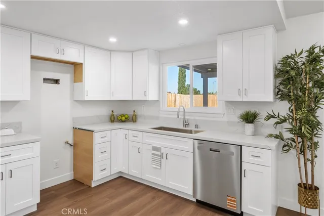 a kitchen with a refrigerator a sink dishwasher and white cabinets with wooden floor
