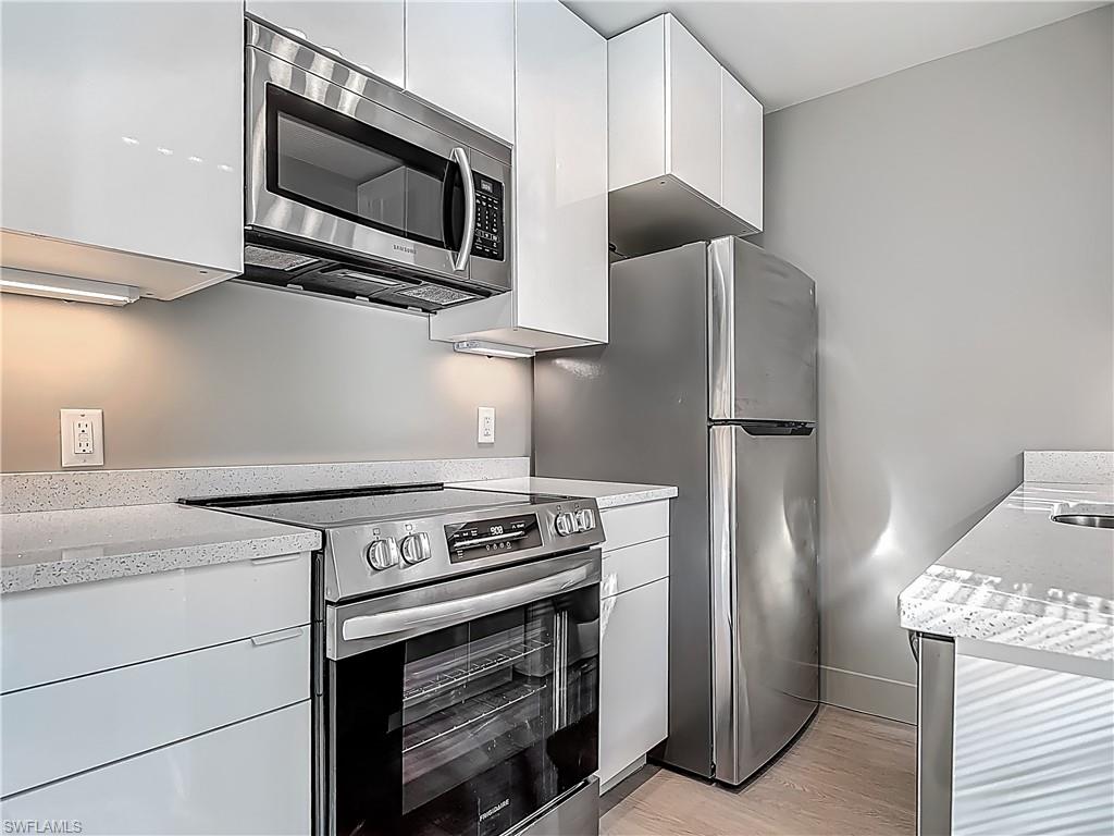 2544 First Street, Unit 102 Fort Myers, FL 33901 - Photo 13 of 26 a kitchen with stainless steel appliances white cabinets and a stove top oven