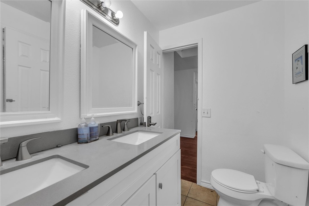 1940 East Highland Road Waxahachie, TX 75167 - Photo 18 of 44 a bathroom with a granite countertop sink a toilet and a mirror