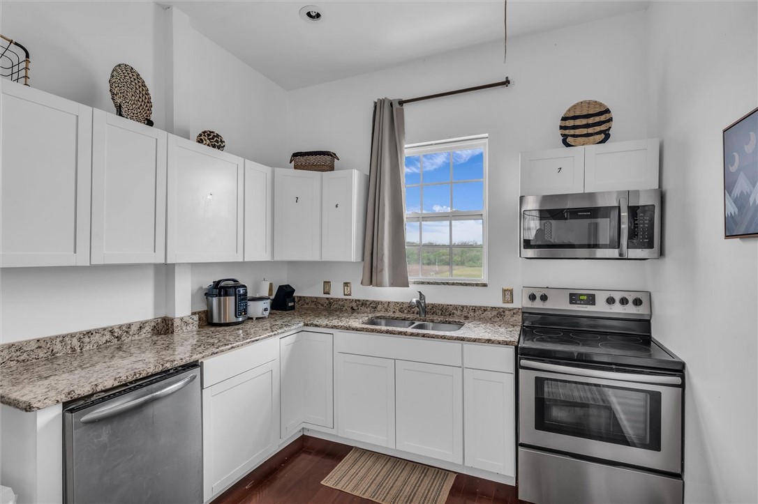 1940 East Highland Road Waxahachie, TX 75167 - Photo 26 of 44 a kitchen with stainless steel appliances granite countertop a sink stove oven a sink and dishwasher with wooden cabinets